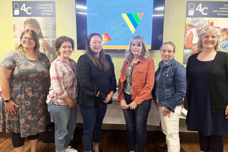 People in front of a monitor that says "Launching into a Program Wide"